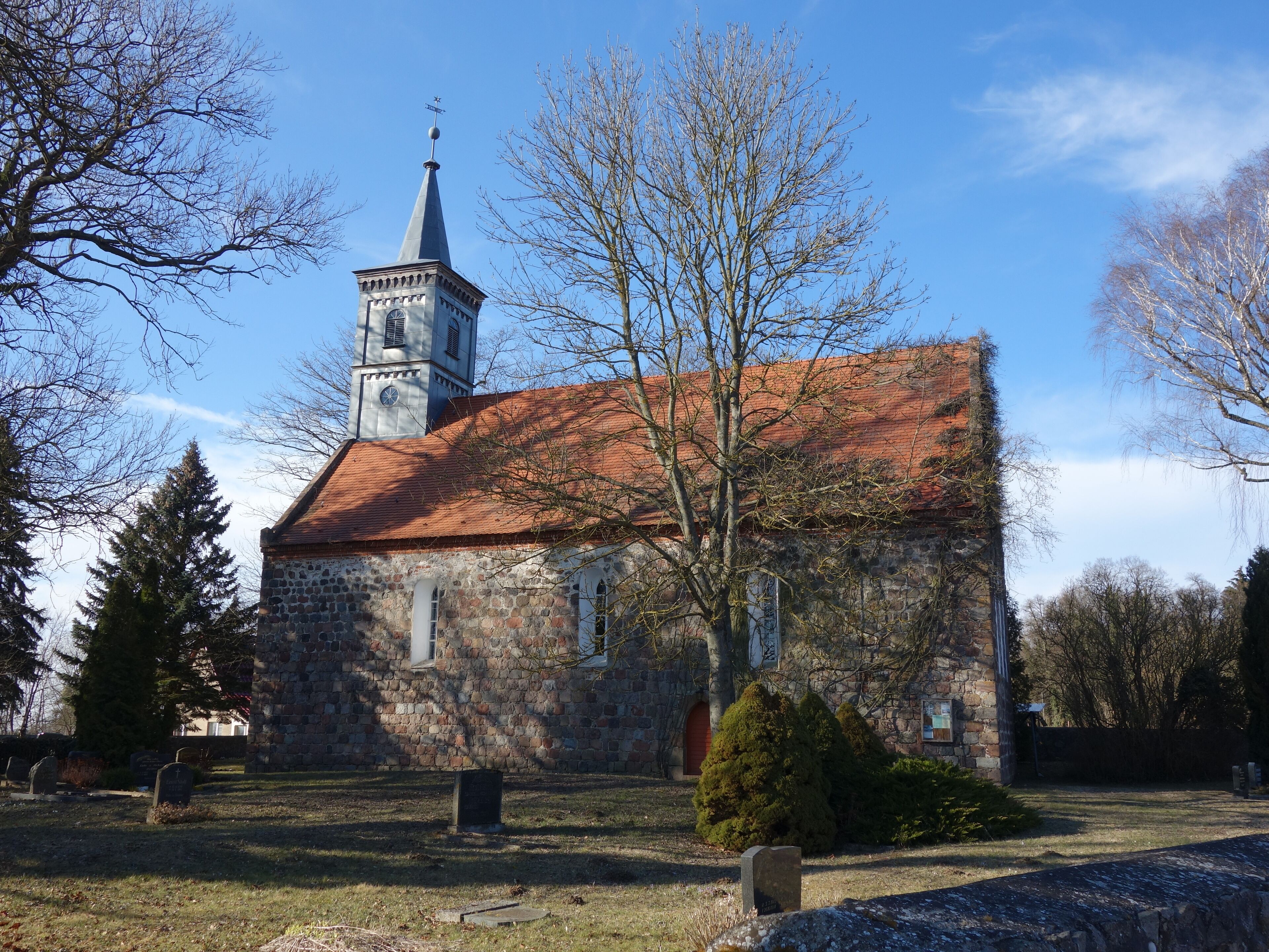 A stone church with a red-tiled roof and a clock tower.