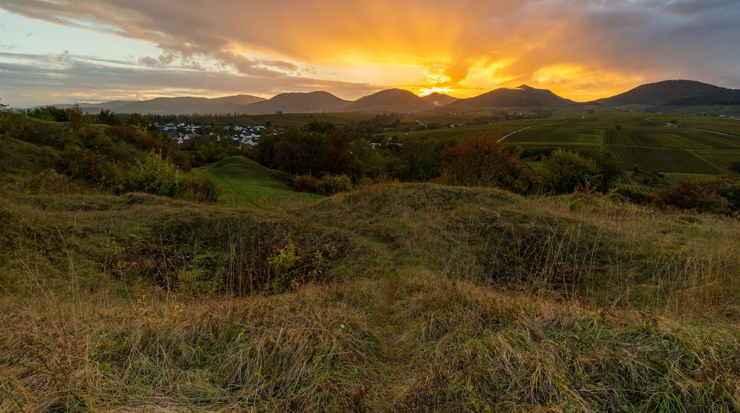 A sunset over rolling hills with a village in the valley.