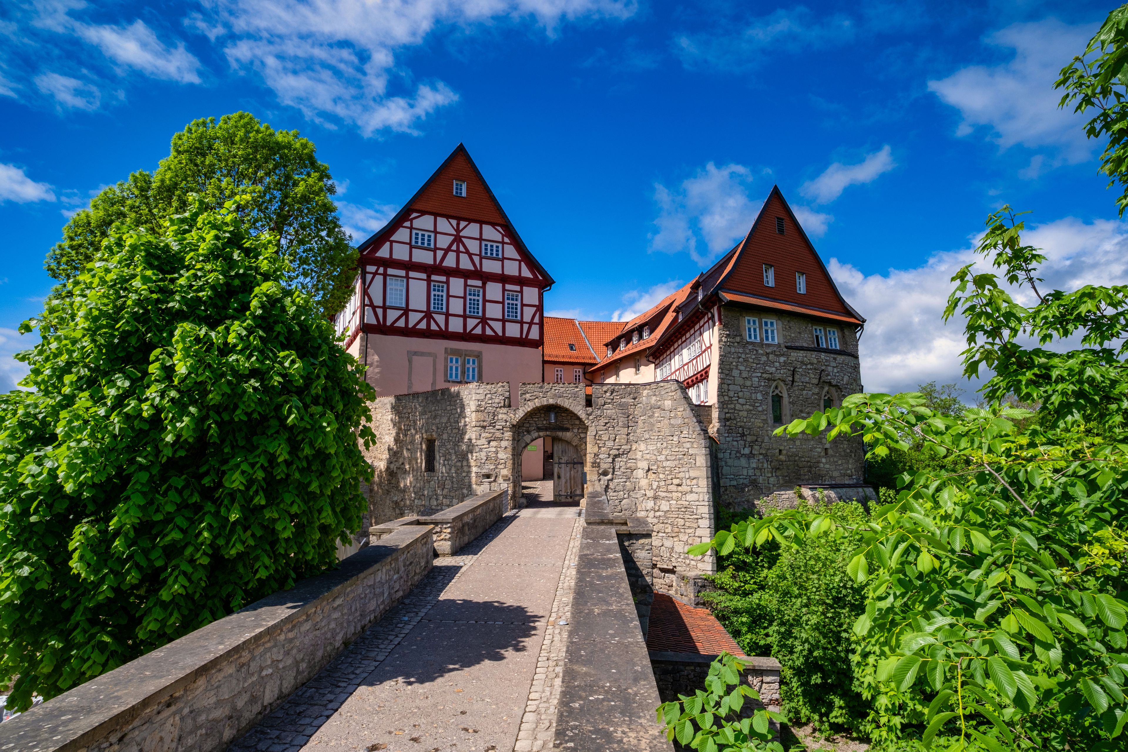 Un bâtiment historique doté d’un toit à forte pente, d’une entrée en pierre et d’un chemin pavé menant à l’entrée.
