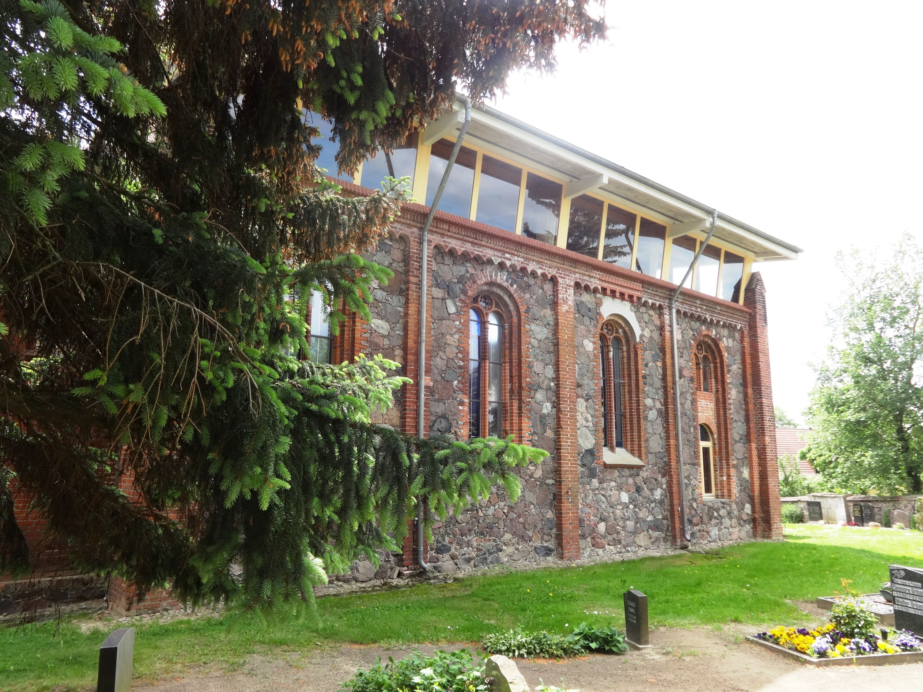 A historic building with arched windows and a stone facade, surrounded by a well-maintained lawn and trees.