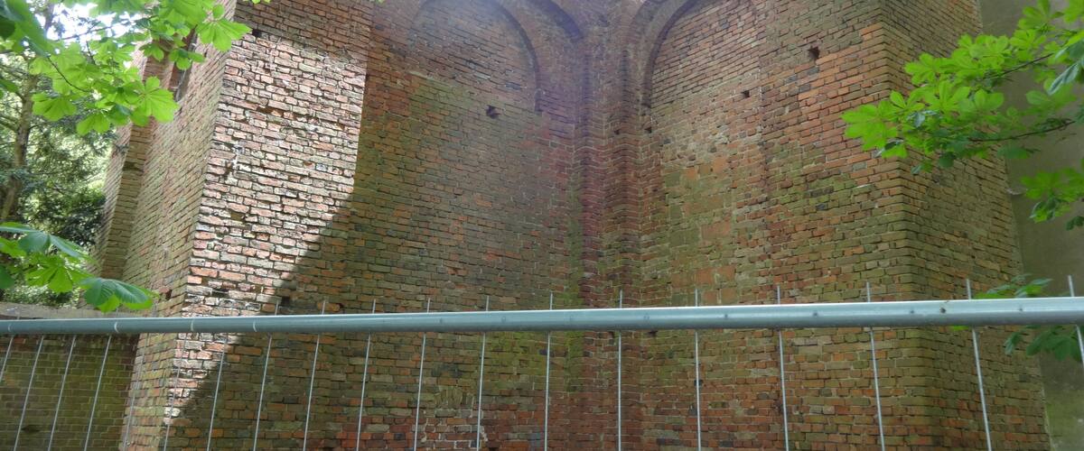 A brick building with arched windows and a metal fence in front.
