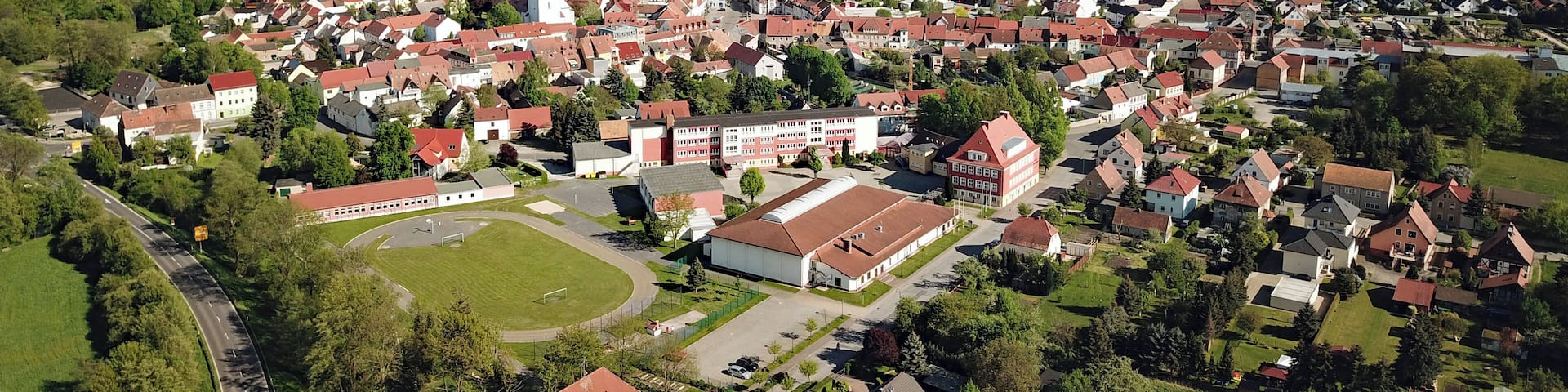 An aerial view of a town with a prominent church, surrounded by residential areas and green fields.