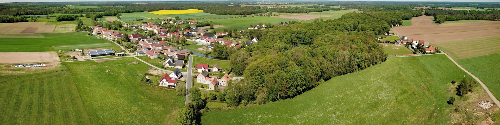 Vista aérea de un pueblo rural con casas, campos y un río.