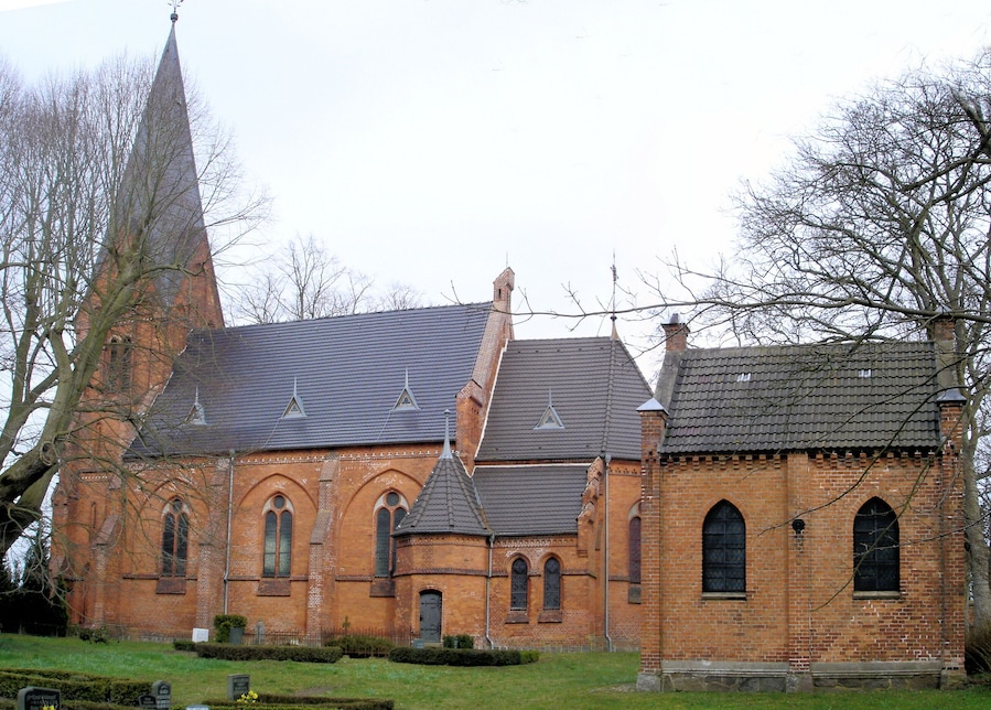 Een historisch kerkgebouw met een hoge spits en rondboogvensters.
