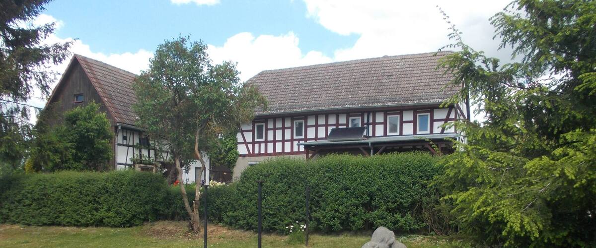 A courtyard with a statue, a hedge, and a building with a tiled roof.