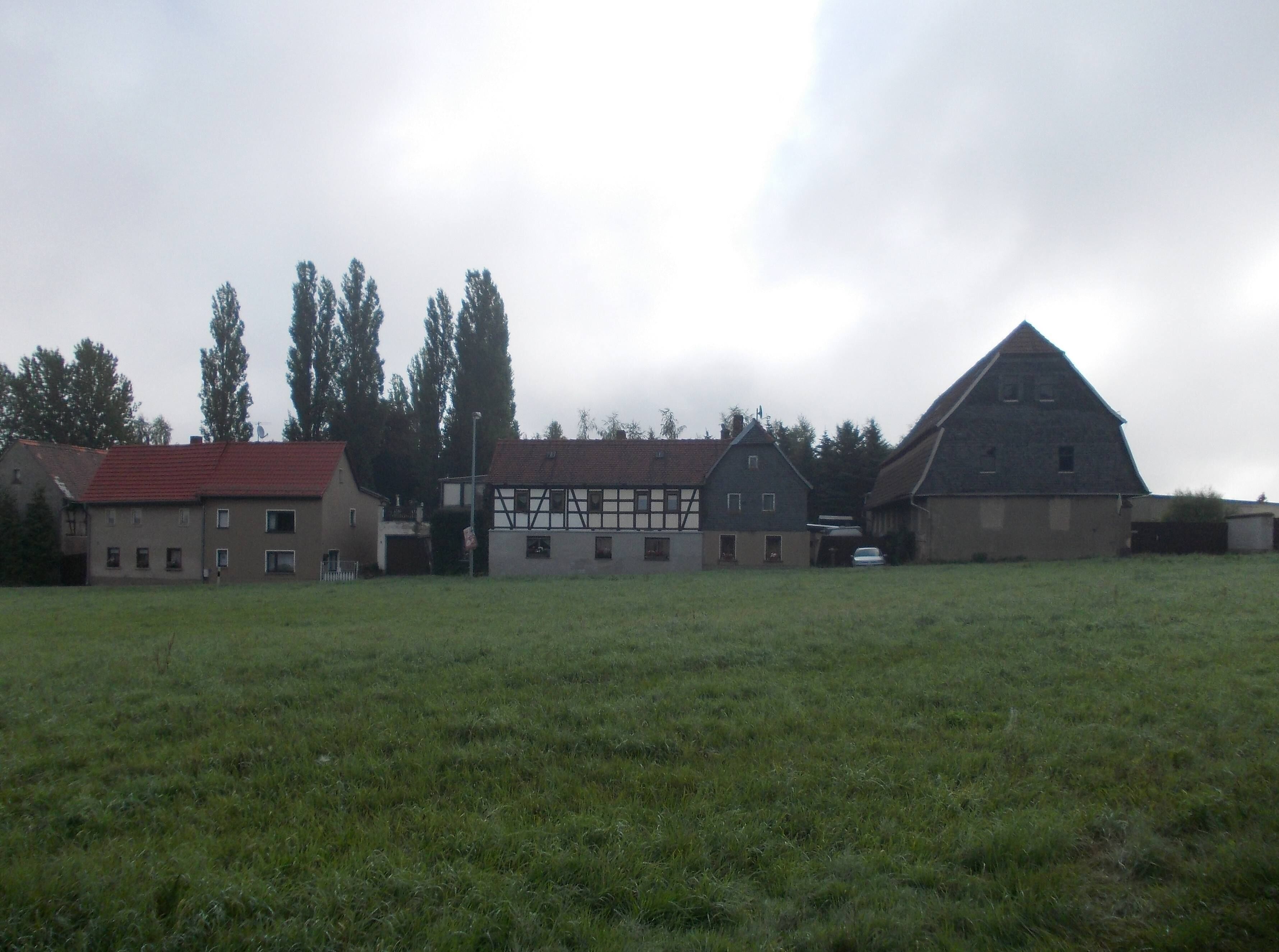 A rural landscape with a barn, a house with a red roof, and a field.