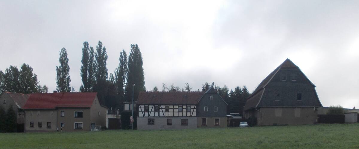 A rural landscape with a barn, a house with a red roof, and a field.