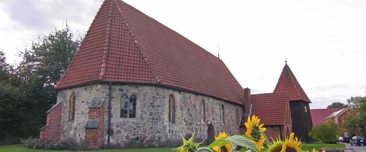 A stone church with a red-tiled roof and a bell tower.