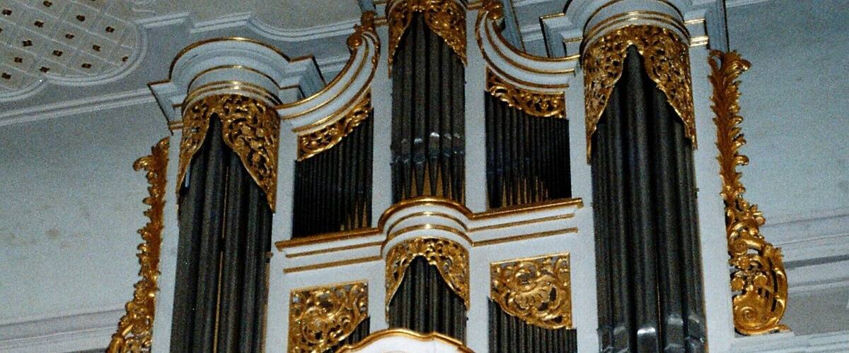 An ornate organ with gold accents and marble columns.