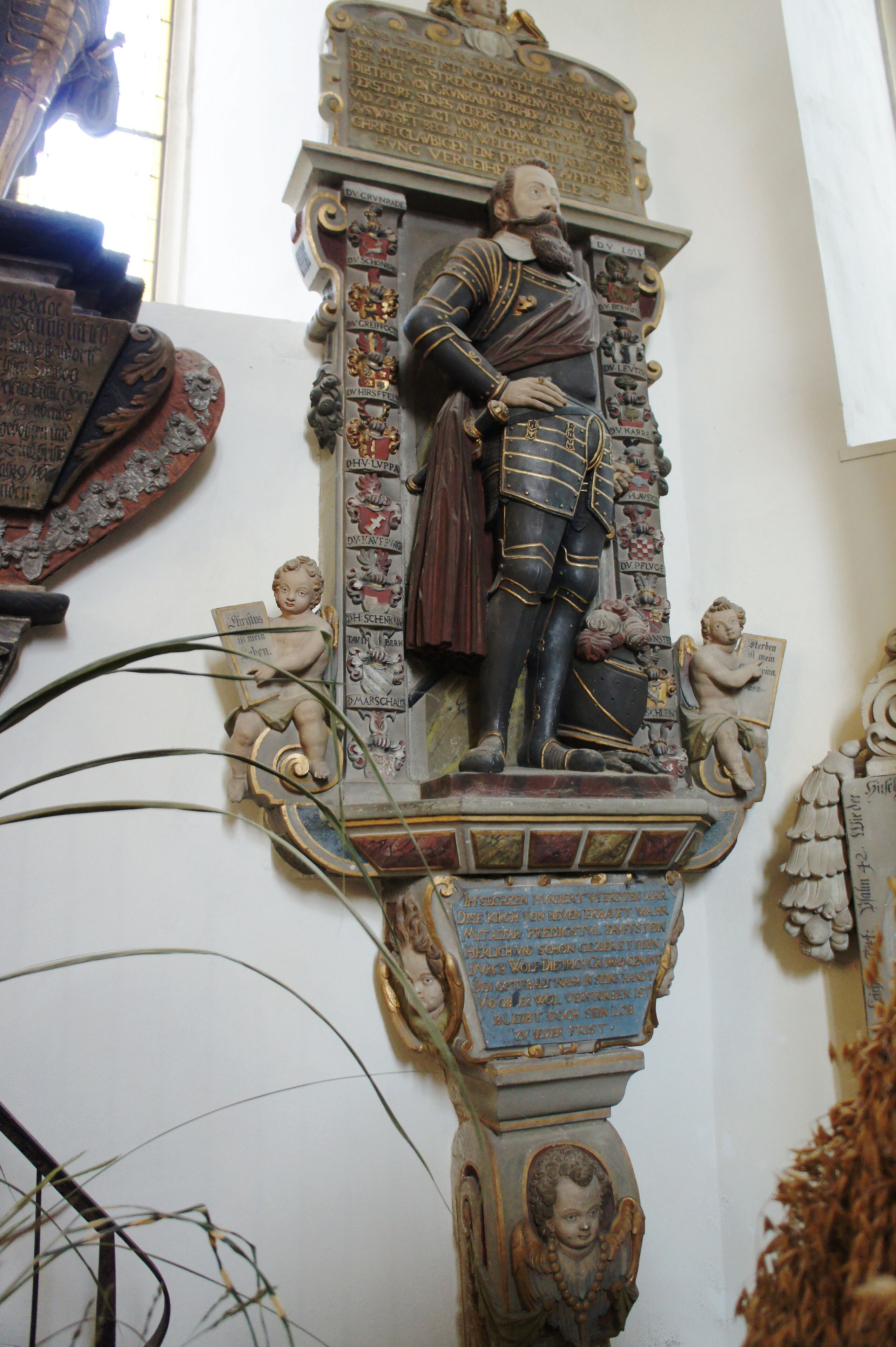 A detailed statue of a historical figure with inscriptions and decorative elements.