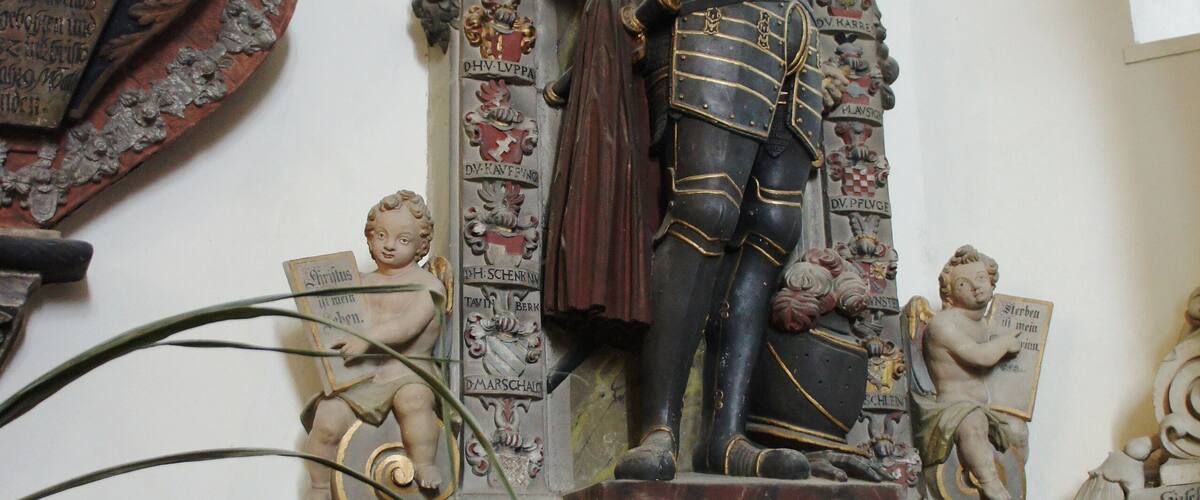 A detailed statue of a historical figure with inscriptions and decorative elements.