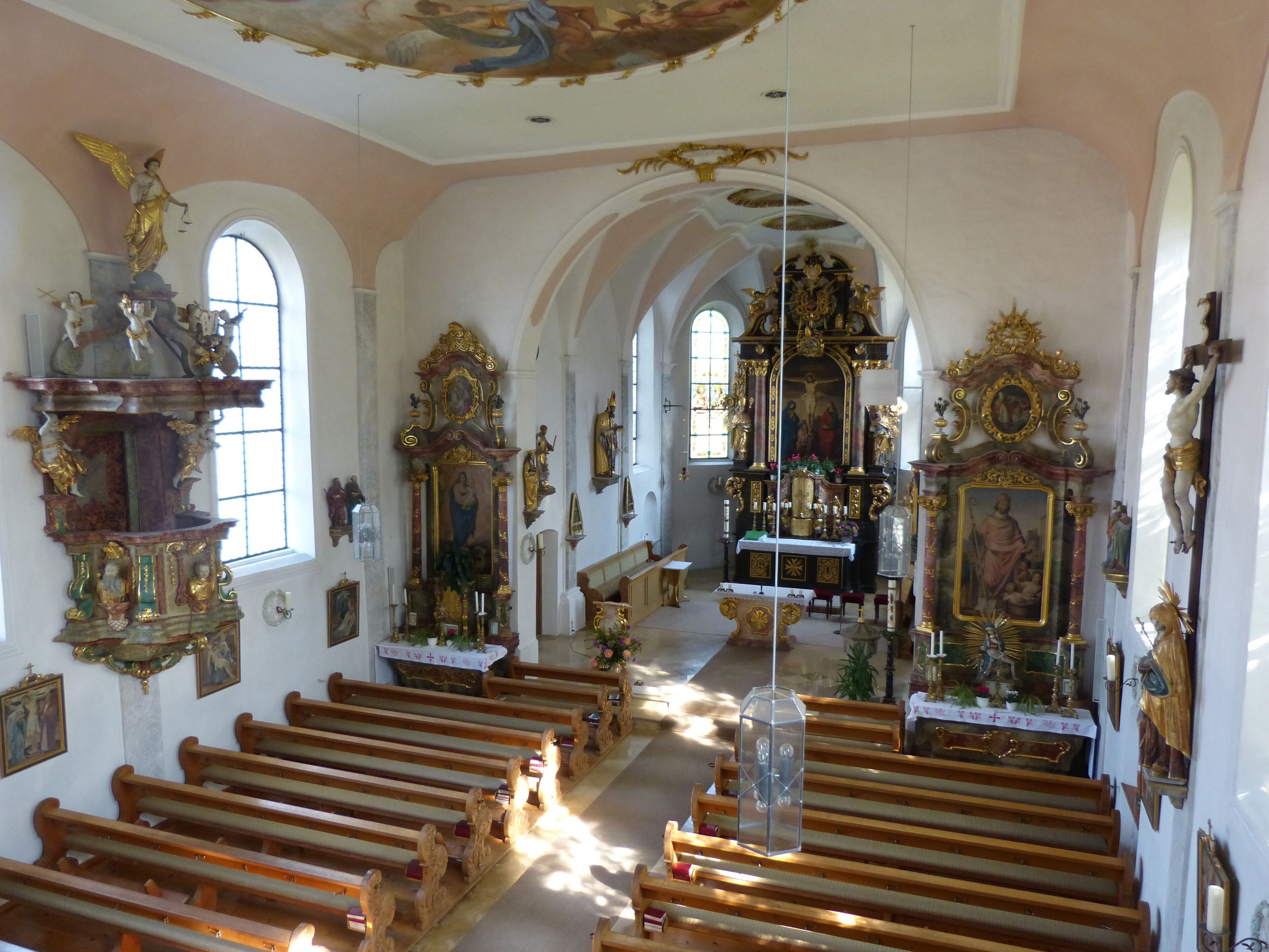 An ornate church interior with wooden pews, a crucifix, and religious statues.