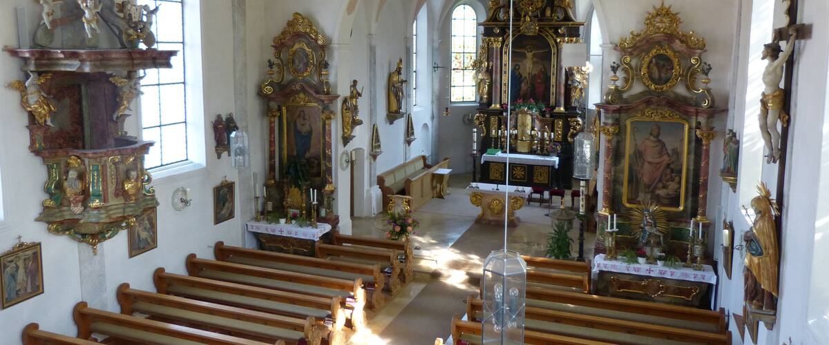 An ornate church interior with wooden pews, a crucifix, and religious statues.