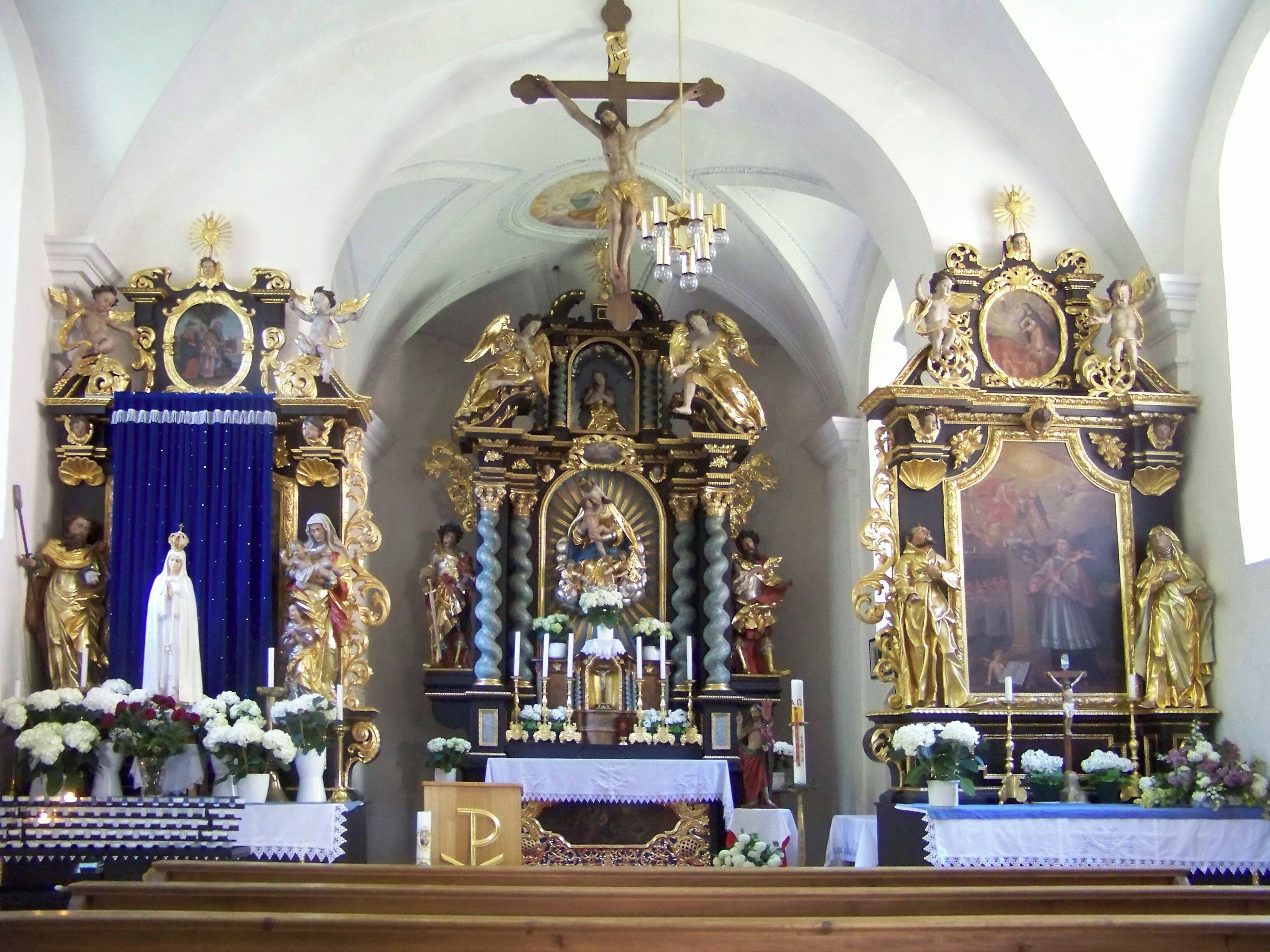 An ornate church altar with religious statues and paintings.