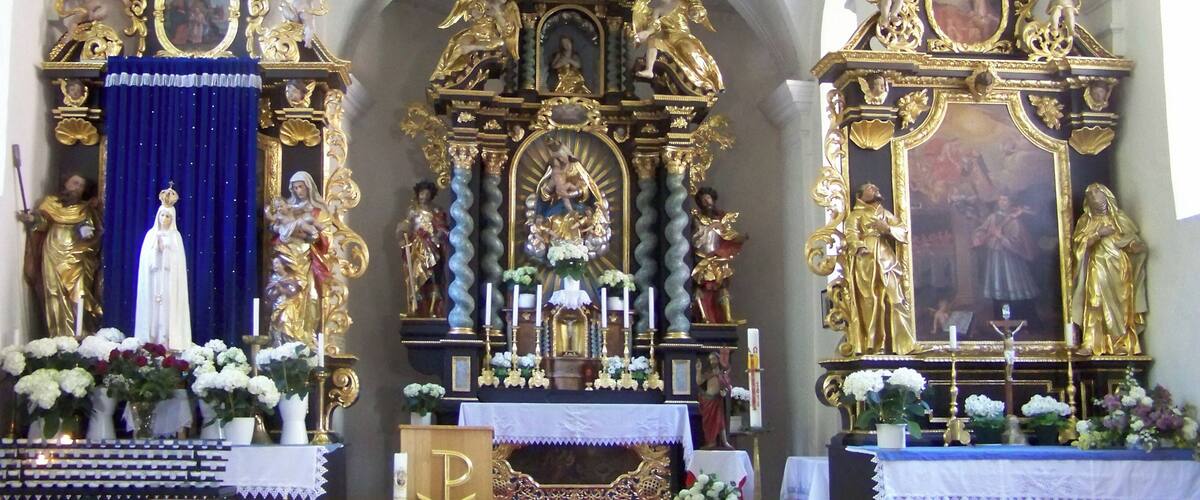 An ornate church altar with religious statues and paintings.