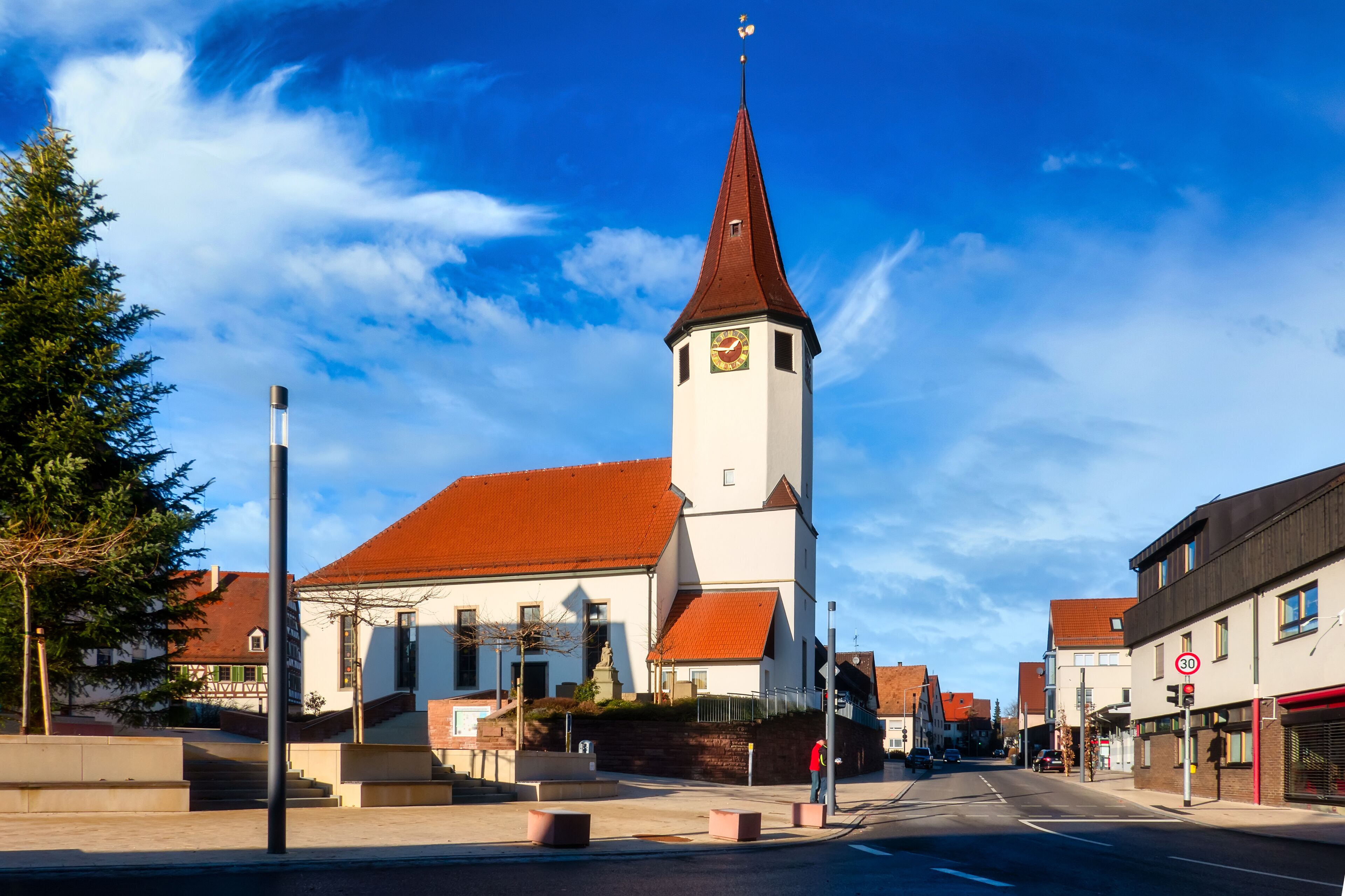 A church with a tall steeple and a clock on its tower, set against a clear blue sky.
