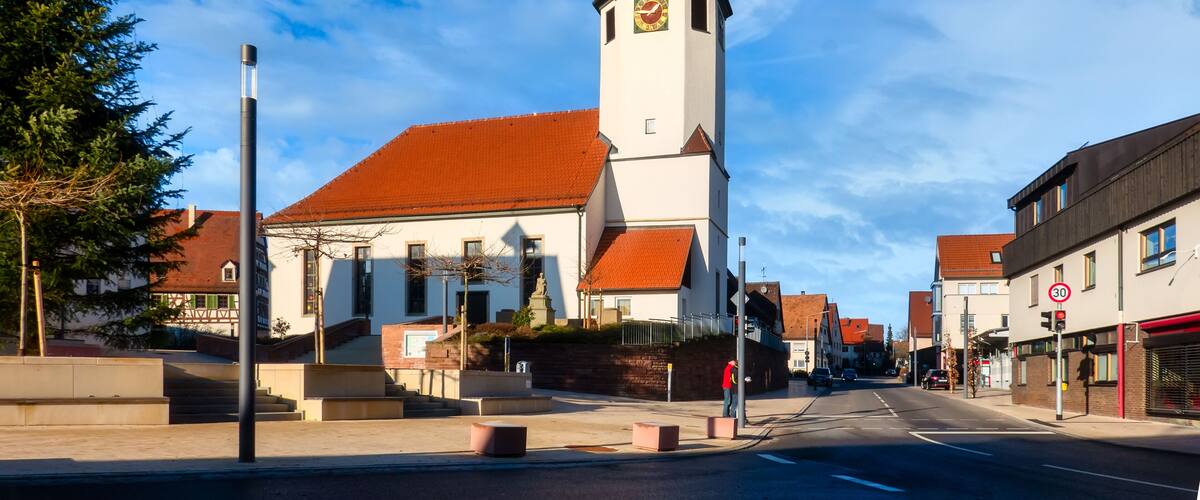 A church with a tall steeple and a clock on its tower, set against a clear blue sky.