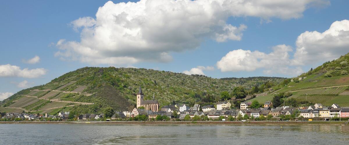 A town by a river with a church and houses on a hillside.