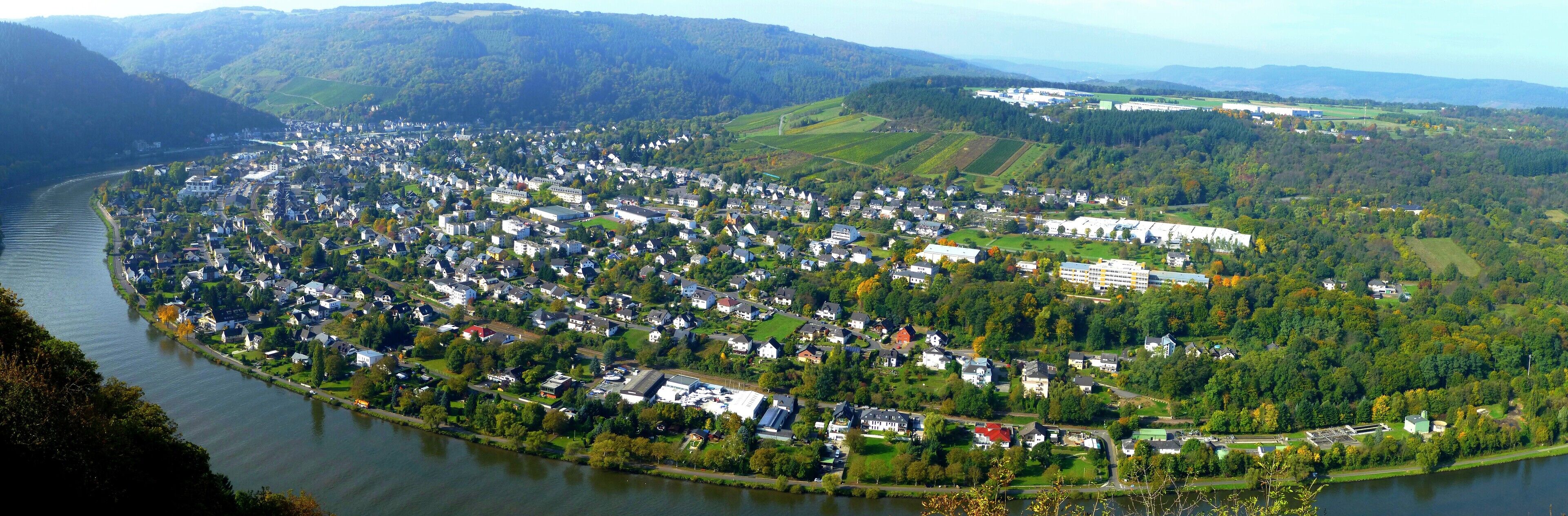 A river winding through a densely populated town surrounded by hills and forests.