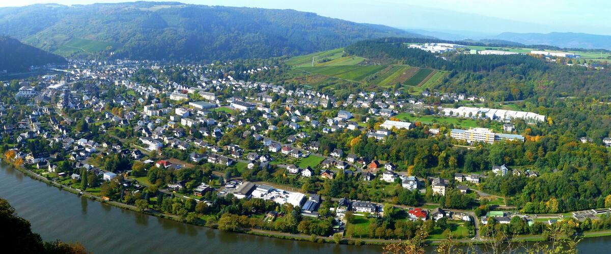 A river winding through a densely populated town surrounded by hills and forests.