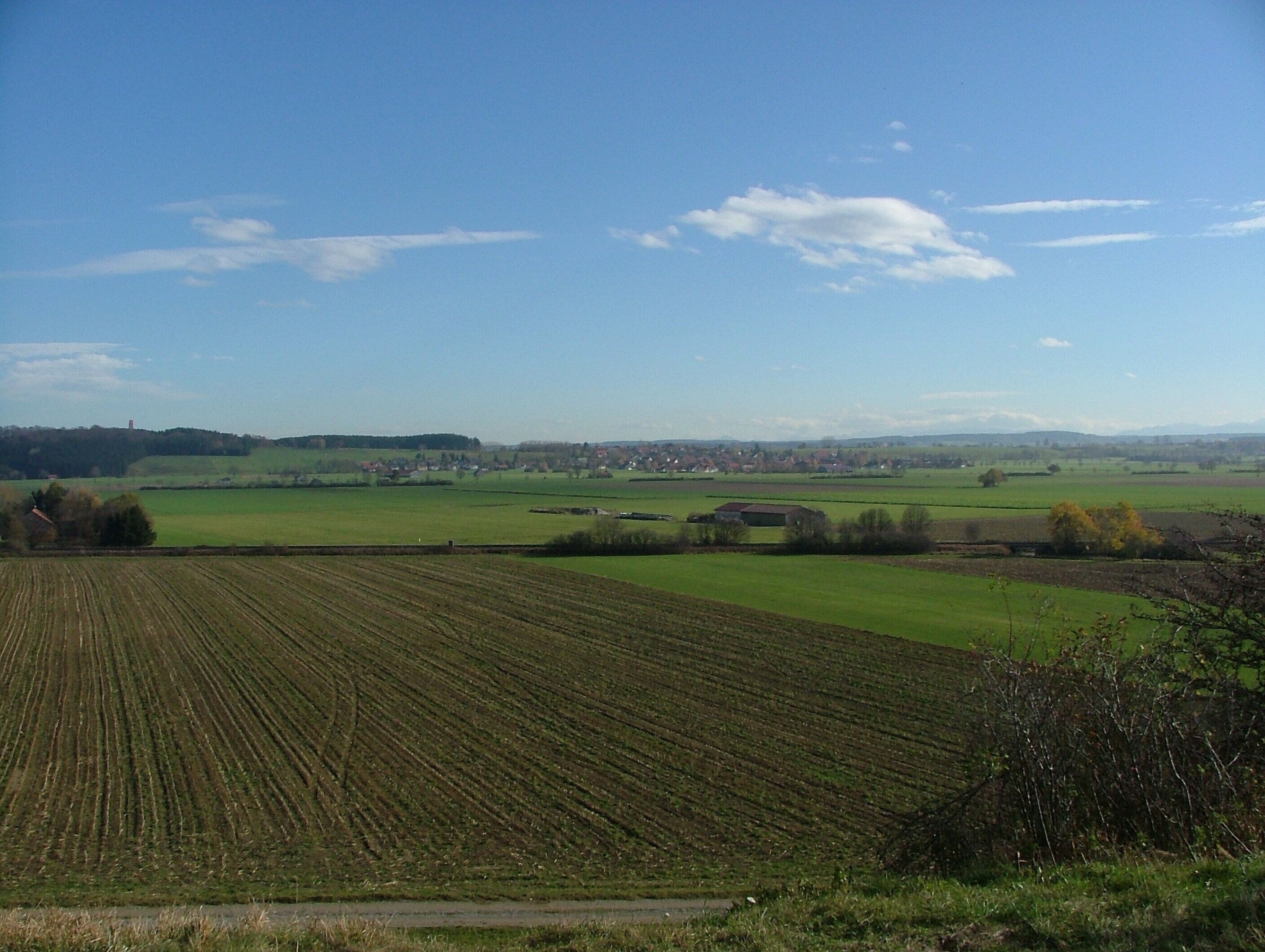 A rural landscape with fields, a distant town, and a clear sky.