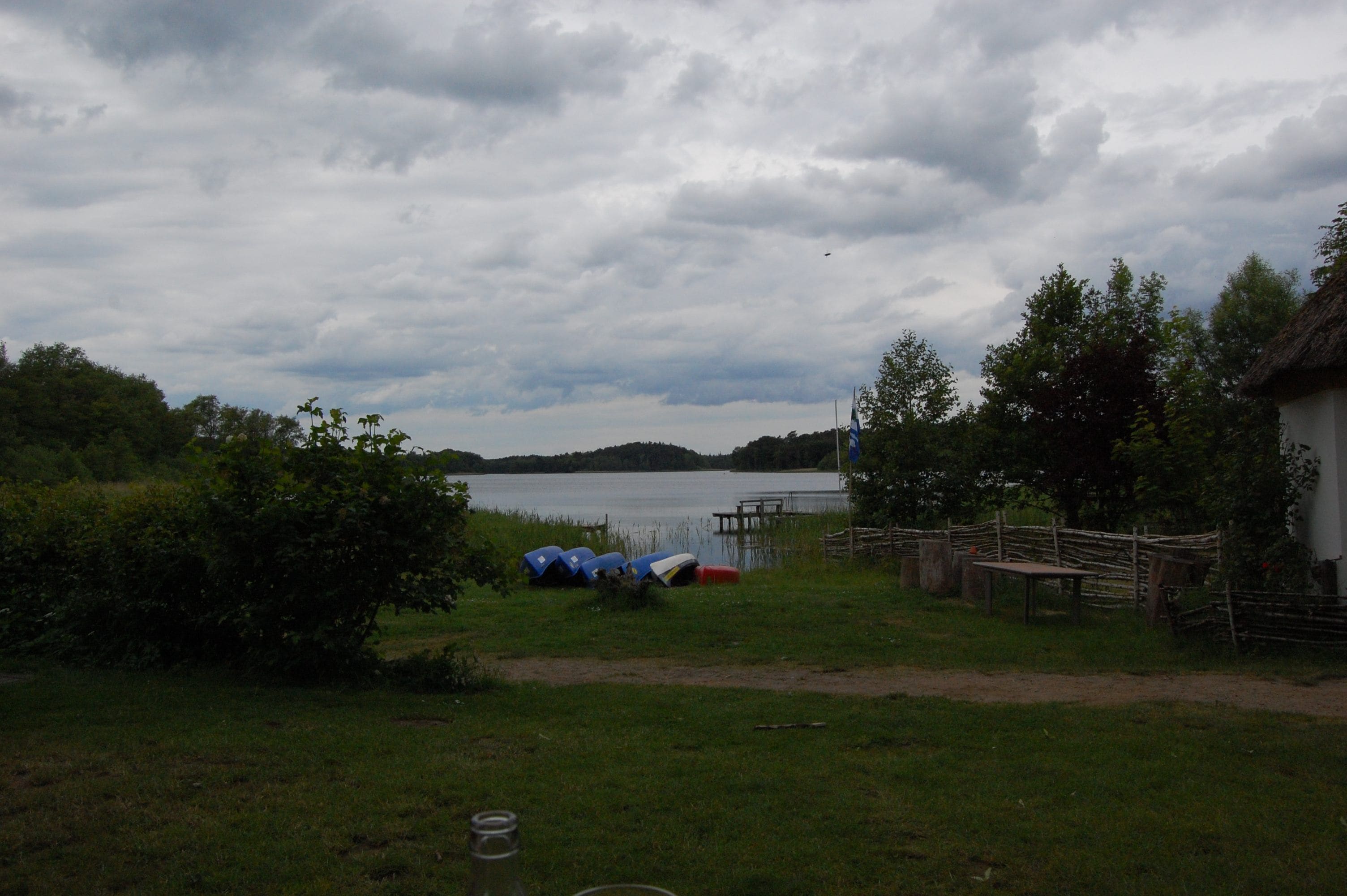 A lakeside campsite with tents, a dock, and a thatched-roof building.