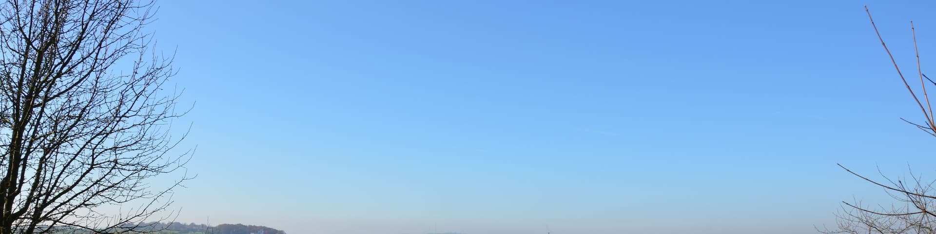 View of the main valley of Gerbrunn between the Happachberg and the Zottenhügel. The course of the main road winding through the vally is hinted by the houses. The roman catholic church St. Nikolaus is clearly visible. Some of the Julius-Maximilians-Universität Würzburg's buildings (Hubland campus) can be made out in the center of the Picture at the end of the build-up area. In the background one can see the Frankenwarte and the radio towers on the Nikolausberg near Wuerzburg.