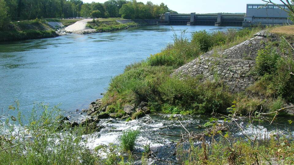 A river with a lock system, surrounded by greenery and a stone structure.