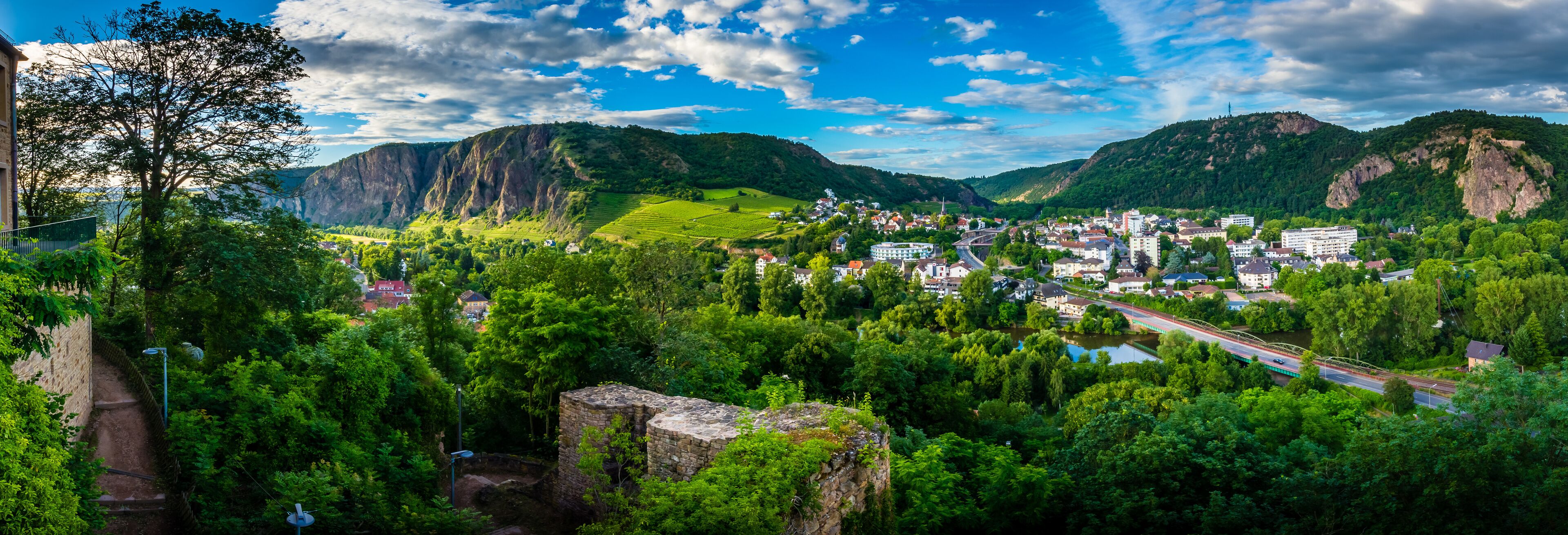 A town nestled in a valley with mountains in the background, a river, and a bridge.