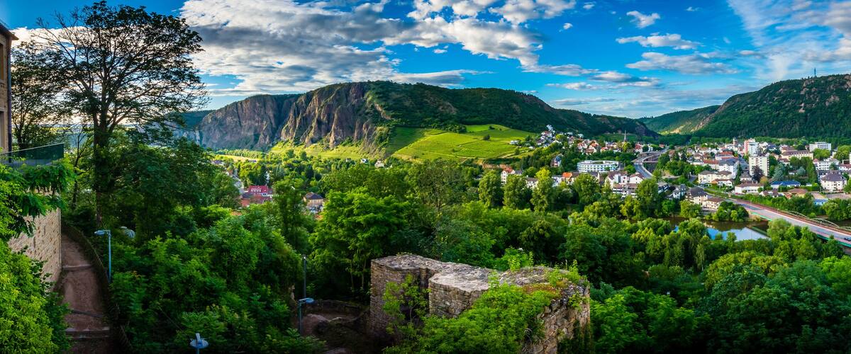 A town nestled in a valley with mountains in the background, a river, and a bridge.