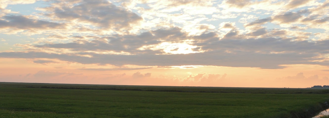 In this picture you can see drainage ditches (also called Grüppen in German). They're typical for the landscape around the North Sea. These drainage ditches in the picture are located on a small flat island in the North Sea called Hallig Hooge. You can see the reflexion of the clouds that are illuminated by the setting sun.