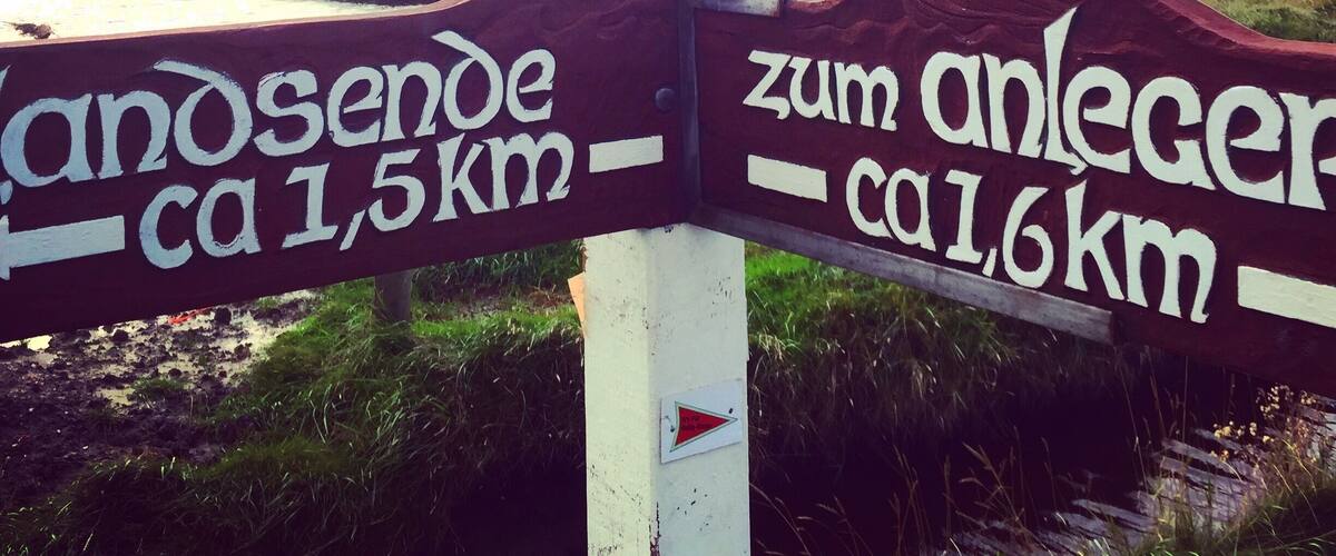 A directional signpost with 'zum anleger ca 1,6km' and 'cantosende ca 1,5km' written on it.
