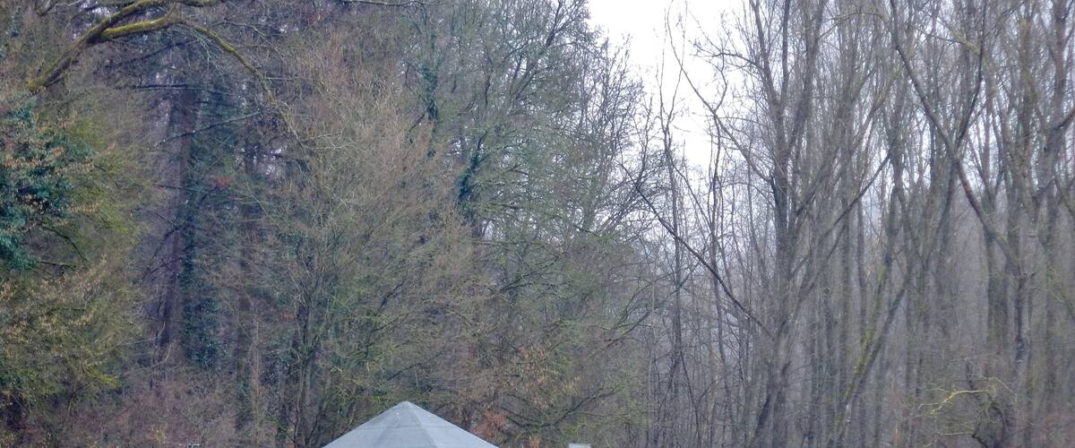 A gazebo by a lake surrounded by trees.