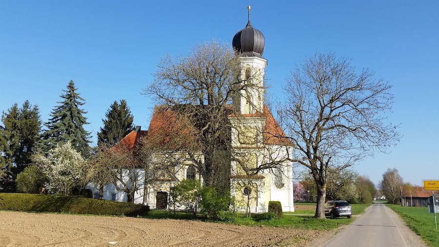 A church with a tall tower and a dome, surrounded by trees and a road.