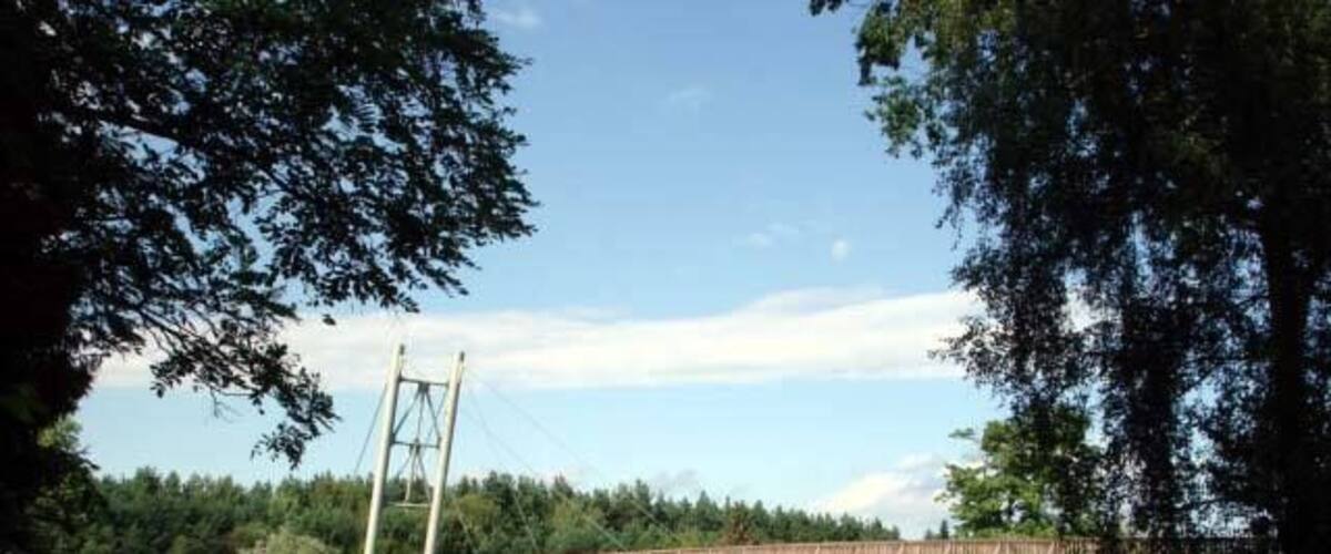 A wooden bridge over a river with a small boat docked on the left.