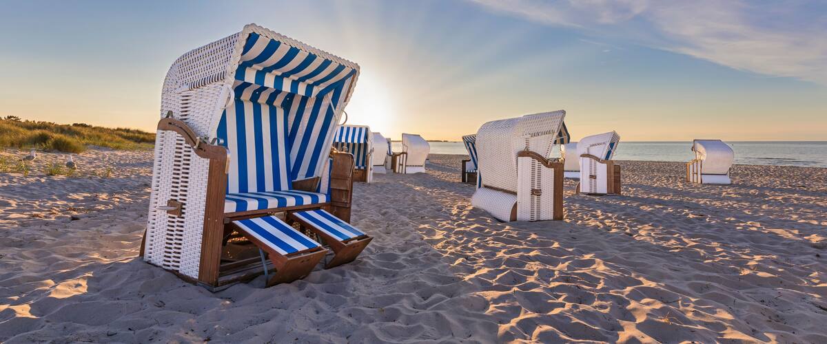 Beach chairs with striped covers on a sandy beach.