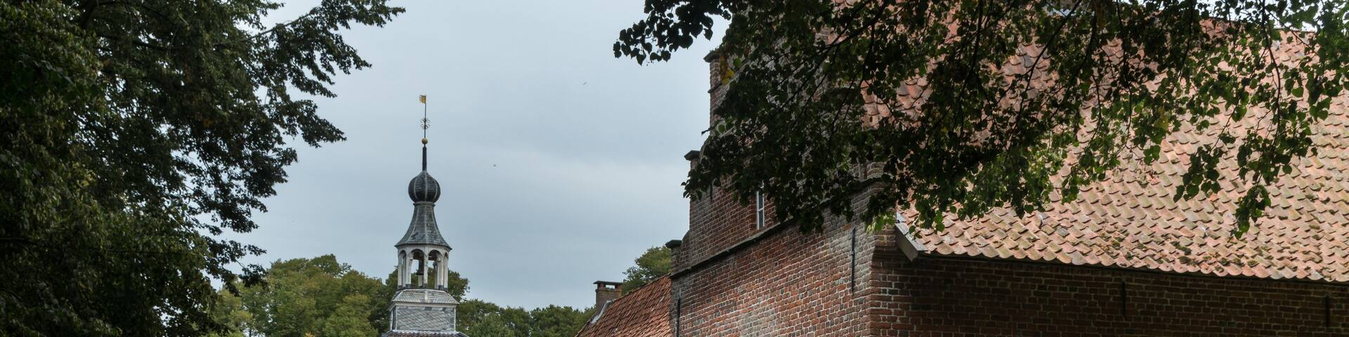 A historic brick building with a tower, a canal, and a bridge.