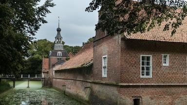 A historic brick building with a tower, a canal, and a bridge.