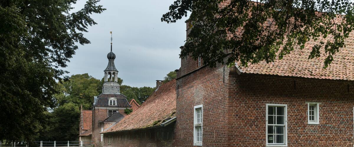 A historic brick building with a tower, a canal, and a bridge.