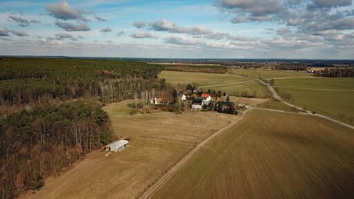 Vista aérea de un paisaje rural con campos, un pequeño grupo de casas e iglesia.