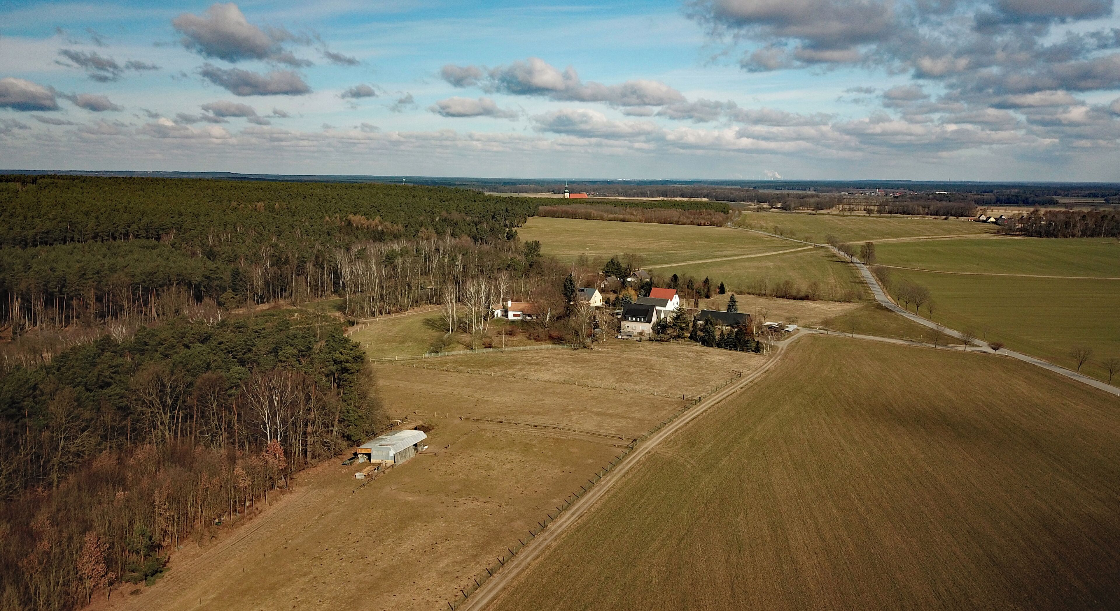 An aerial view of a rural landscape with fields, a small cluster of houses, and a church.