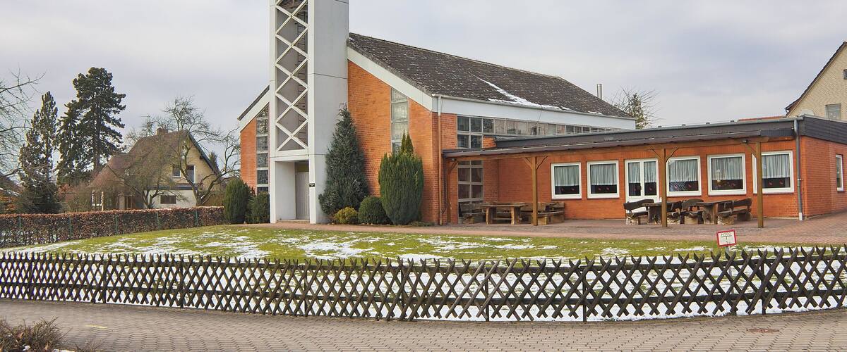 A church with a tall steeple and a brick building with large windows.