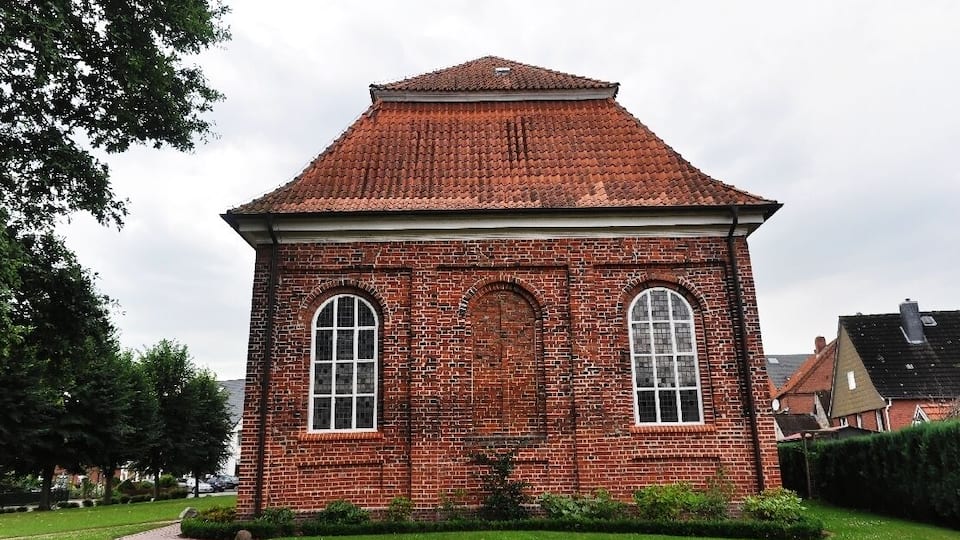 A red brick church with a tiled roof and arched windows.