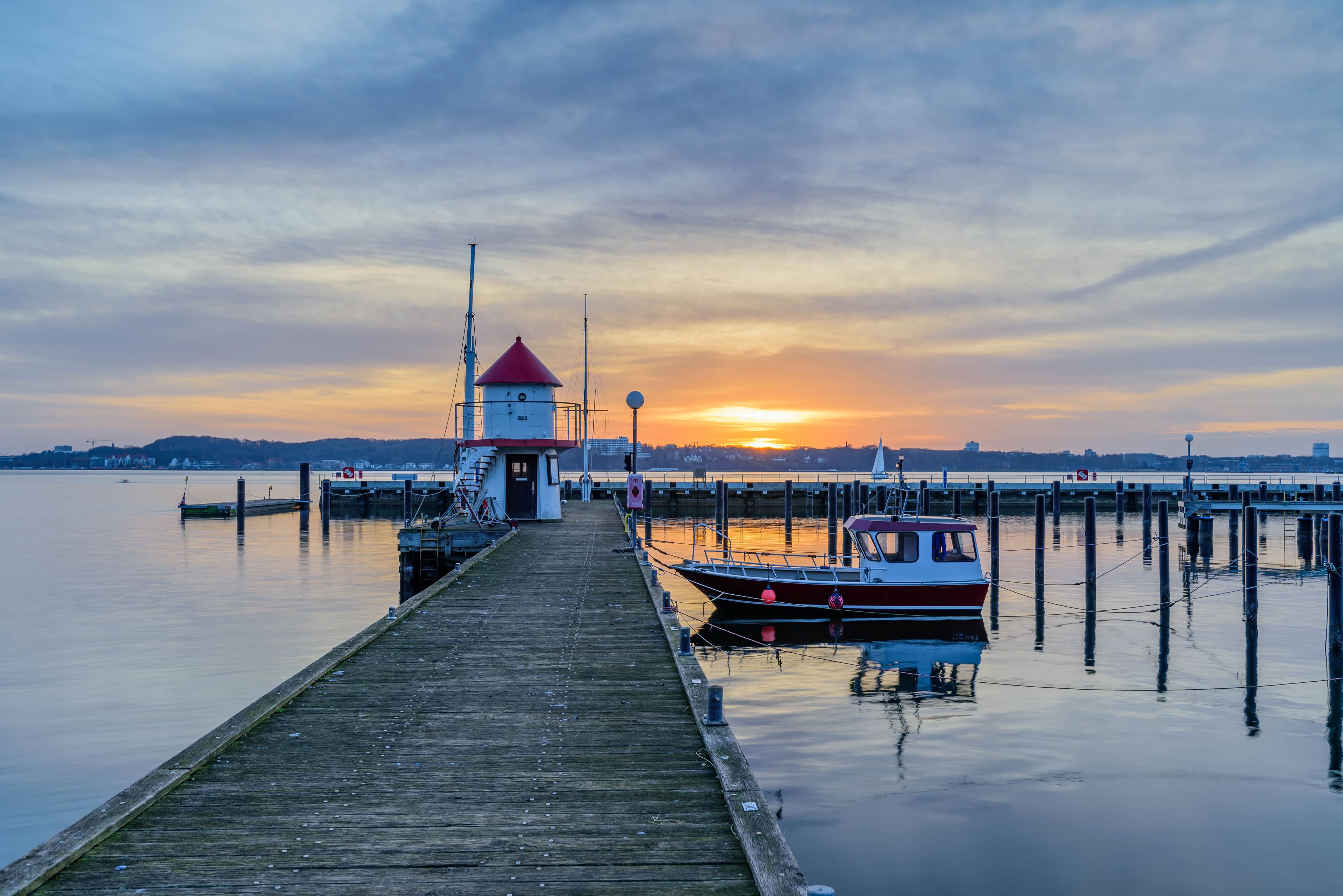 View of the idyllic marina of Mönkeberg with the red and white tiny lighthouse, the "Juliusturm", the landmark of the Mönkeberg marina. View of Kiel Fjord and its lighthouse.Sailing boat on Kiel Fjord
