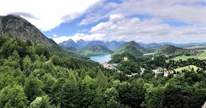 A mountainous landscape with a lake, forested areas, and a small village.