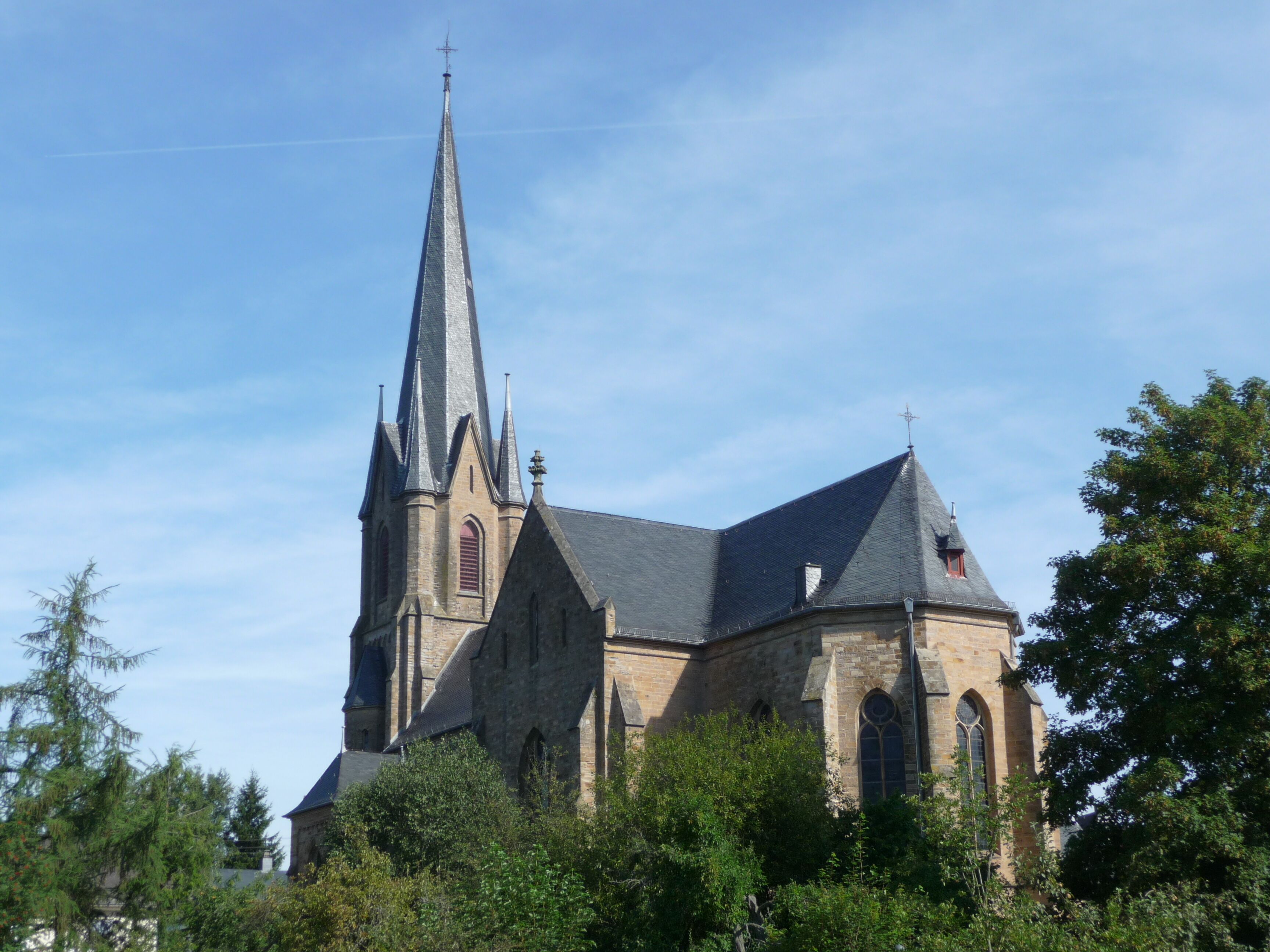 A church with a tall spire and a smaller tower.