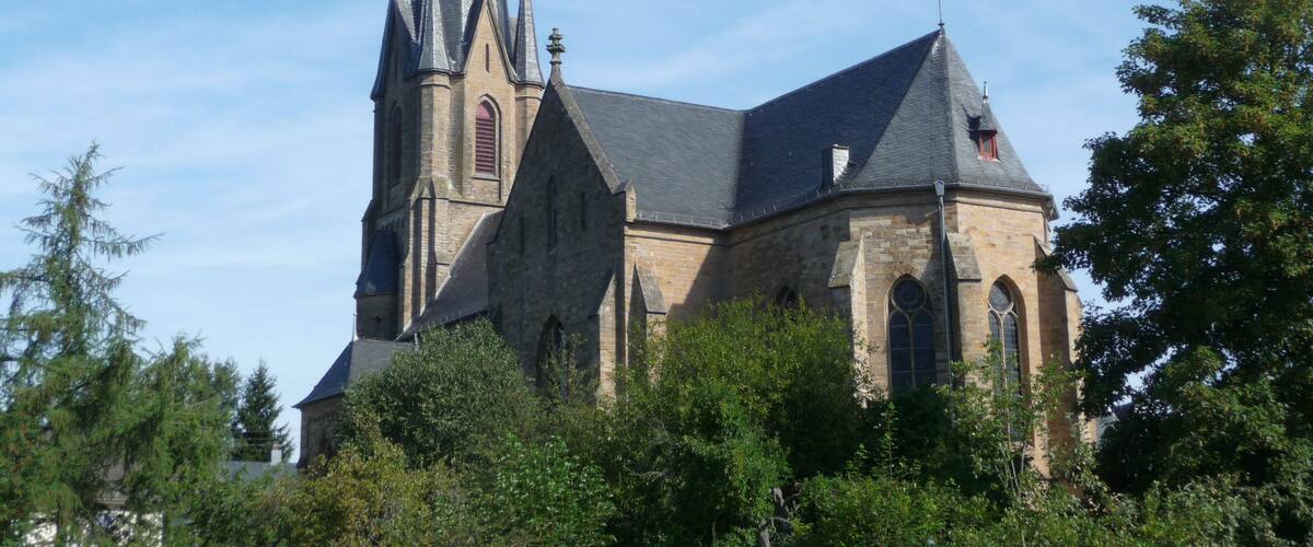 A church with a tall spire and a smaller tower.