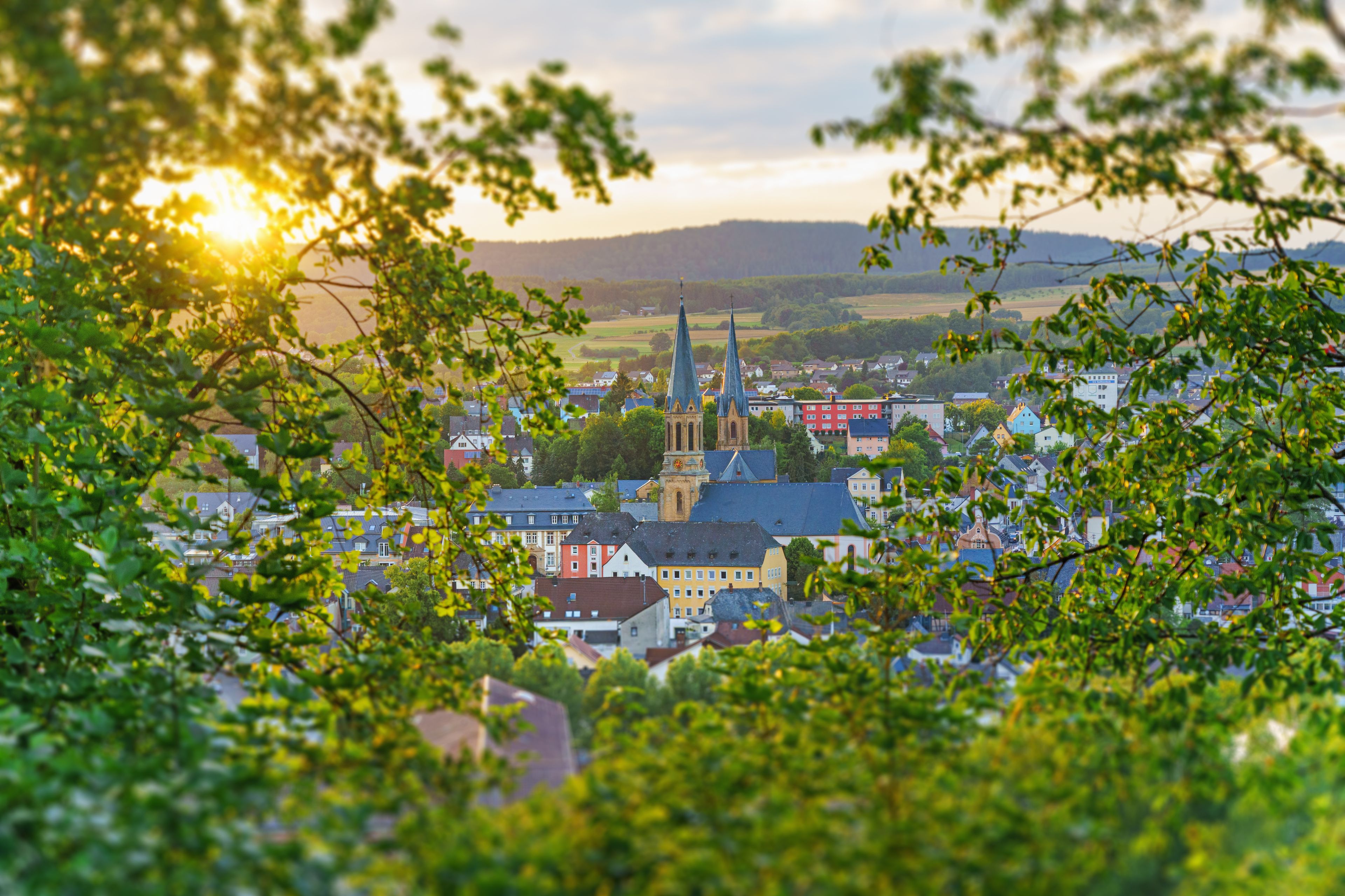 A town with a prominent church and spires, surrounded by greenery and buildings.