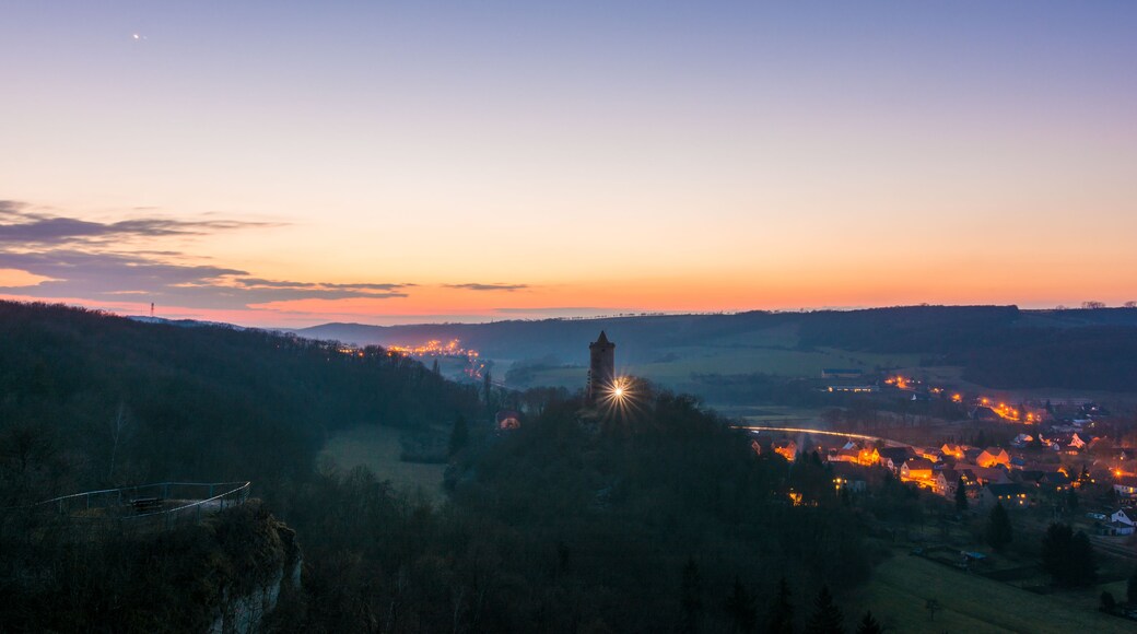 Atardecer sobre un valle con una torre y un pequeño pueblo.