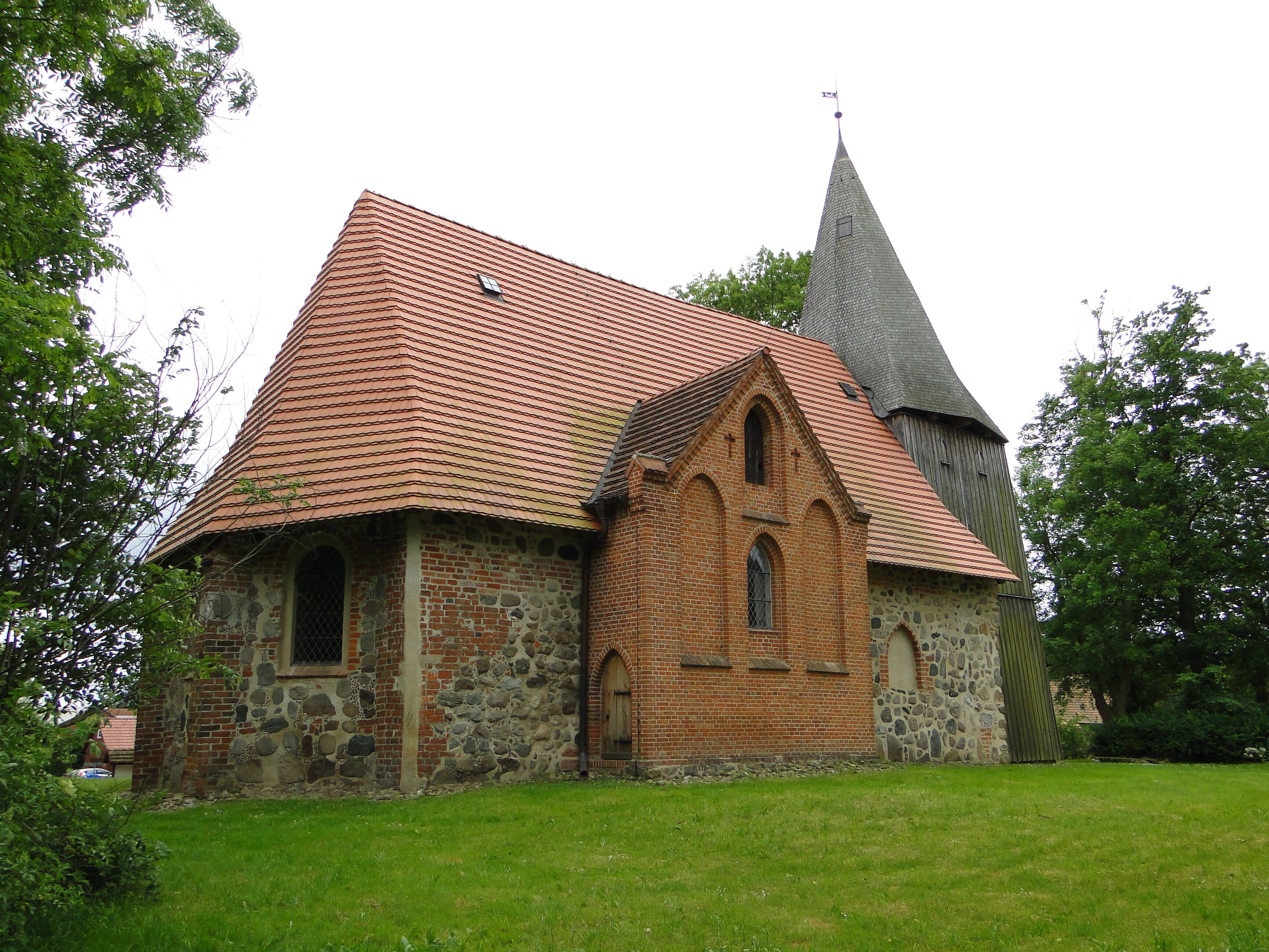 A church with a red-tiled roof and a stone building with a pointed tower.